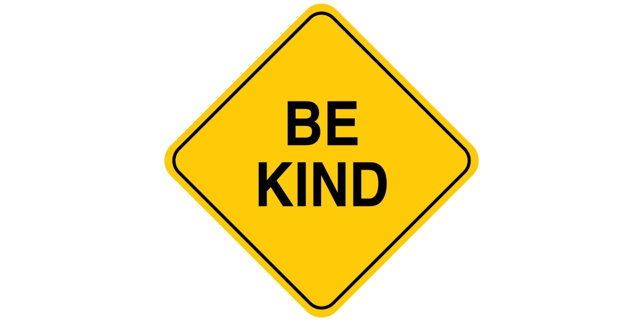 Yellow diamond shaped sign with the letters BE Kind on it in black